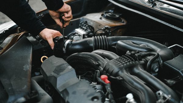 close up of an engine in a car, with a hand twisting a wrench in the corner